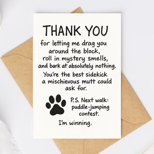 May include: A white greeting card with the words "THANK YOU" in bold black letters. The card has a paw print and humorous text about a dog's antics. It rests on a brown envelope.