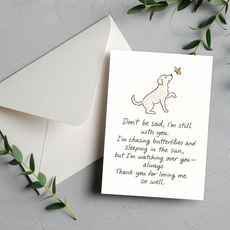 May include: A white greeting card with a dog illustration and a butterfly, accompanied by a white envelope. The card features the text: "Don't be sad, I'm still with you..." A heartfelt sympathy card.