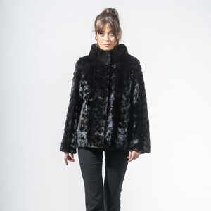 May include: A black faux fur coat with a high collar and long sleeves. The coat is buttoned up and worn with black pants and black heels. The coat has a textured appearance.