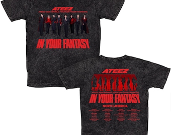 May include: A black, acid-wash t-shirt featuring the text "ATEEZ IN YOUR FANTASY" in red. The front of the shirt displays a group of people in red and black outfits. The back of the shirt also has the text "ATEEZ IN YOUR FANTASY" and a list of cities.