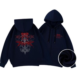 May include: Navy blue zip-up hoodie with a hood and front pockets. The back features a red and white graphic design with the word "domin" and other text. The front of the hoodie also has the word "domin" in red.