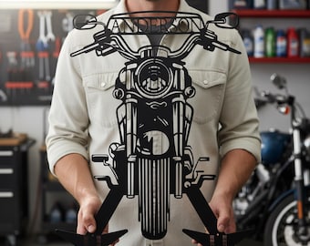 May include: Black metal motorcycle wall art with the name "ANDERSON" across the handlebars. The motorcycle features a detailed design of the engine, headlight, and handlebars. The art is held by a person in a light-colored shirt.