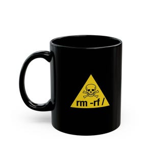 May include: A black ceramic mug featuring a yellow triangle warning sign on the front. Inside the triangle is a black skull and crossbones icon above the text rm -rf / printed in a bold, black, sans-serif font.