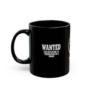 May include: A black ceramic mug featuring white text that reads WANTED FOR DEPLOYING TO PRODUCTION ON A FRIDAY. The mug has a standard cylindrical shape with a curved handle on the left side and a smooth, glossy finish throughout the exterior surface.