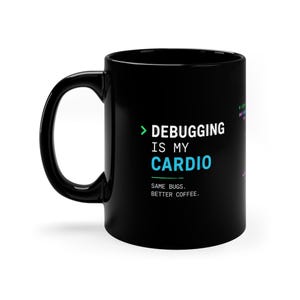 Könnte beinhalten: Ein schwarzer Keramikbecher mit dem weißen Text DEBUGGING IS MY CARDIO, einer grünen Klammer und blauem Text, gefolgt von dem weißen Text SAME BUGS. BETTER COFFEE. Der Becher hat einen geschwungenen Henkel auf der linken Seite und eine glatte Oberfläche.