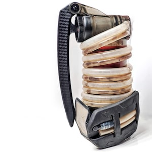 May include: A black and clear device featuring a carbon fibre handle and a series of clear, coiled tubes. The device has a red interior and a black base with a small, silver component. The handle is textured.