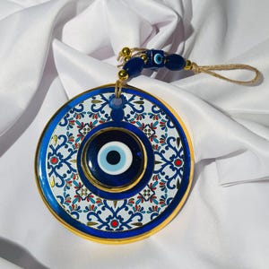 Handgemaakte blauwglazen wandhanger boze oog: gouden accenten, jute touw