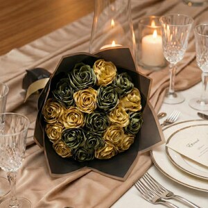 Handmade forever flower bouquet featuring olive green and golden yellow satin ribbon roses wrapped in elegant translucent brown paper. A luxury long lasting floral gift designed for weddings, anniversaries, Mother’s Day, and romantic occasions. Displayed in a modern neutral interior setting with jewelry box and soft natural light. A timeless artificial rose bouquet that never fades and serves as a keepsake floral arrangement.