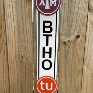 May include: A white sign with the letters "BTHO" in black, with a maroon circle with a white "TAM" logo above and an orange circle with a white "tu" logo below.