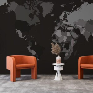 Puede incluir: Escena de diseño interior con dos sillones naranjas, una pequeña mesa blanca con un jarrón y un mural de mapa del mundo negro. Una escultura decorativa blanca con una corona está a la izquierda.