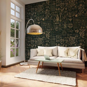 Op de afbeelding: Een moderne woonkamer met een lichtgekleurde bank, een kleine tafel en een vloerlamp. De kamer heeft een behang met een patroon in donkergroen en goud, een houten vloer en een zacht tapijt. Een laptop staat op de tafel.