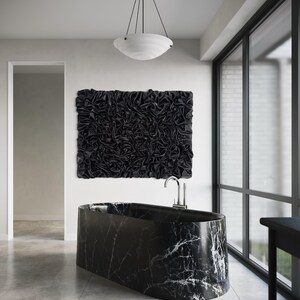 Könnte beinhalten: Ein modernes Badezimmer mit einer schwarzen Marmorbadewanne mit weißen Adern. Über der Wanne hängt ein großes, strukturiertes schwarzes Wandkunstwerk. Eine weiße Leuchte hängt von der Decke. Große Fenster lassen natürliches Licht herein.