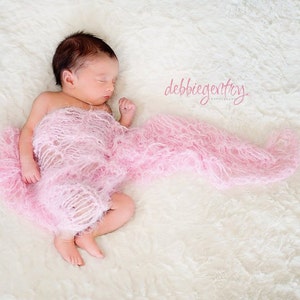 Peut inclure: Un nouveau-n&eacute; dort paisiblement envelopp&eacute; dans une couverture rose et moelleuse. Le b&eacute;b&eacute; est allong&eacute; sur une surface blanche et moelleuse. Le texte "debbie gentry photography" est visible dans le coin sup&eacute;rieur droit de l'image.