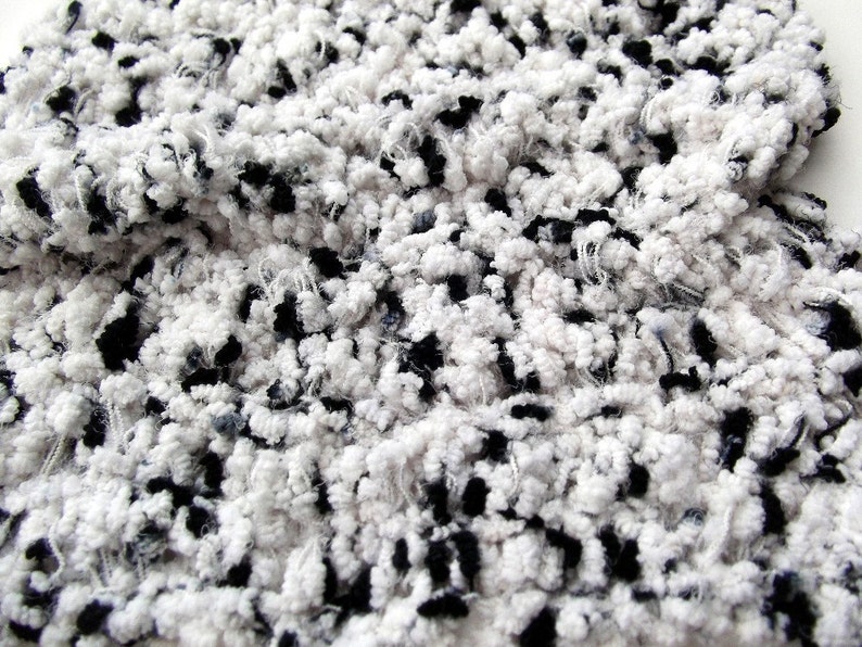 May include: Close-up of a white and black fuzzy fabric with a textured, fluffy surface.