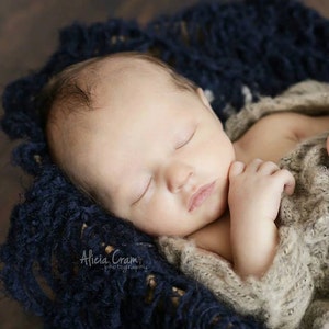 Peut inclure: Un nouveau-n&eacute; dort paisiblement dans une couverture en tricot bleu. Le b&eacute;b&eacute; porte un pull en tricot beige et a la main sous le menton.