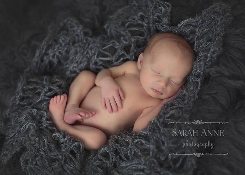 Peut inclure: Un nouveau-n&eacute; dort paisiblement sur une couverture moelleuse grise. Le b&eacute;b&eacute; est enroul&eacute; sur lui-m&ecirc;me, les bras et les jambes repli&eacute;s. Les yeux du b&eacute;b&eacute; sont ferm&eacute;s et son visage est d&eacute;tendu.