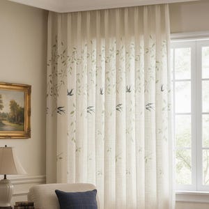 May include: Cream-coloured linen curtain featuring a design of green leaves and blue birds. The curtain is hanging in front of a window. The curtain is in a living room setting.