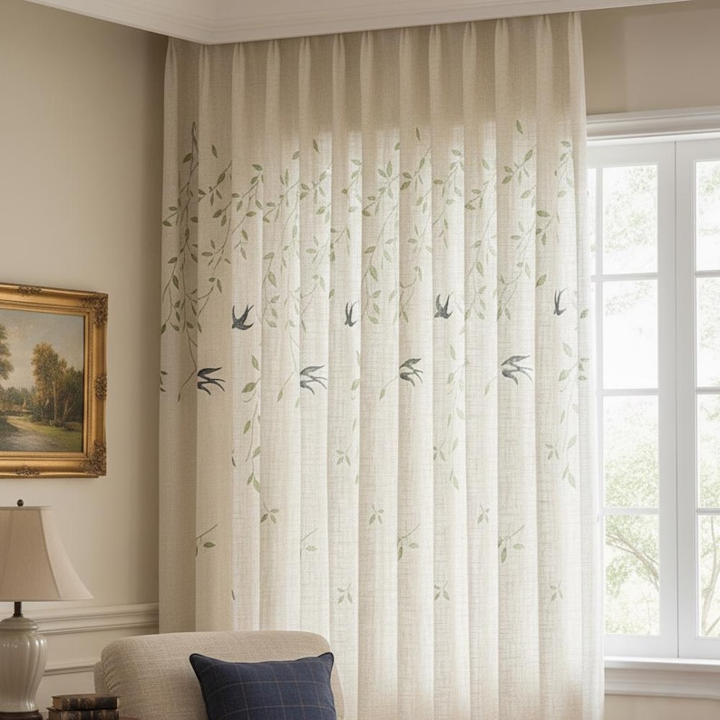 May include: Cream-coloured linen curtain featuring a design of green leaves and blue birds. The curtain is hanging in front of a window. The curtain is in a living room setting.