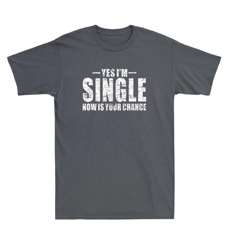 May include: Dark gray t-shirt with the text "YES I'M SINGLE NOW IS YOUR CHANCE" in distressed white lettering. The shirt is a crew neck style and appears to be made of a soft cotton blend.