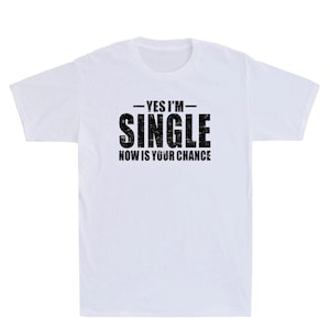 May include: White t-shirt with the text "YES I'M SINGLE NOW IS YOUR CHANCE" in black, bold letters. The text is centered on the front of the shirt. The shirt has a crew neck and short sleeves.