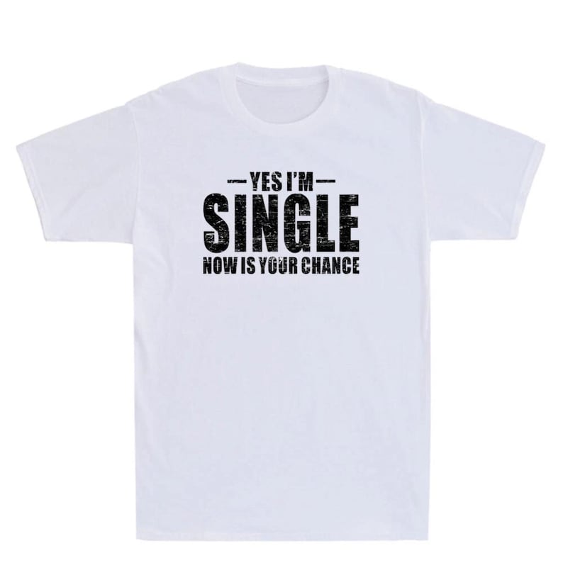 May include: White t-shirt with the text "YES I'M SINGLE NOW IS YOUR CHANCE" in black, bold letters. The text is centered on the front of the shirt. The shirt has a crew neck and short sleeves.