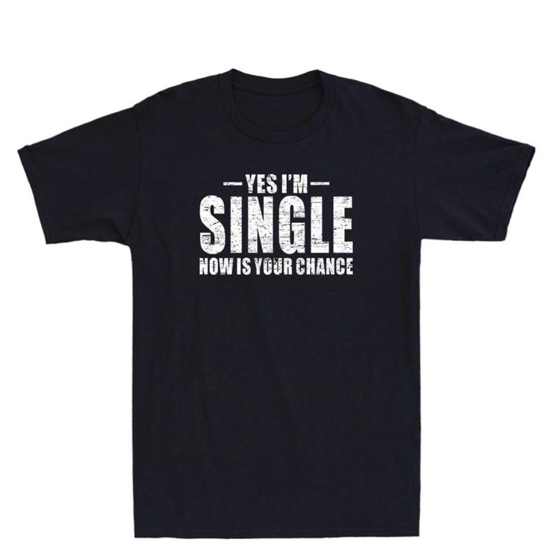 May include: Black t-shirt with the white text "YES I'M SINGLE NOW IS YOUR CHANCE". The text has a distressed, vintage look. The shirt is a classic crew neck style.