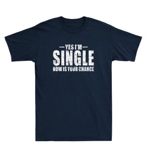 May include: Navy blue t-shirt with the white text "YES I'M SINGLE NOW IS YOUR CHANCE". The text has a distressed, vintage look. The shirt is a short-sleeved crew neck.