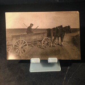 Antikes Schwarzweißfoto, Pferdewagen, ländliches Dorfleben, historischer Transport, landwirtschaftliches Erbe, klassische Landschaftsszene