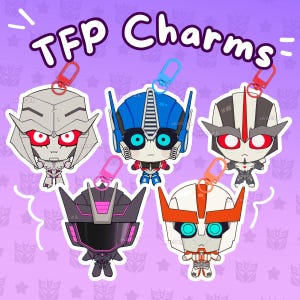 May include: Five acrylic charms featuring stylized robot character heads with colorful details, including red, blue, and pink accents. Each charm has a small plastic clip attached to the top. The text TFP Charms is printed in purple above the characters.