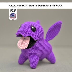 May include: A handmade purple crochet creature with a pink tongue and black eyes. The crochet animal has a wide open mouth and two large ears. The text "CROCHET PATTERN - BEGINNER FRIENDLY" is at the top of the image.