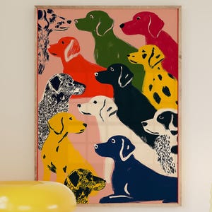 May include: A framed art print featuring a colorful illustration of various dog breeds in shades of red, green, yellow, and blue. A yellow mushroom-shaped lamp, a striped mug, and a blue dish with lemons sit on a white cabinet.