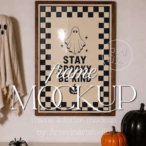 Op de afbeelding: Een rechthoekige wandlijst met een donkere houten afwerking met een poster met een zwart-witte geblokte rand. De poster bevat een centrale illustratie van een geest, kleine sterren, een pompoen en de tekst STAY SPOOKY BE KIND in zwarte inkt.