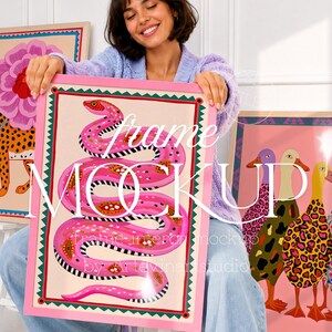 May include: A framed art print with a vibrant pink snake design, detailed with patterns, set on a cream background and framed in pink. Other framed animal art prints are also visible in the image.