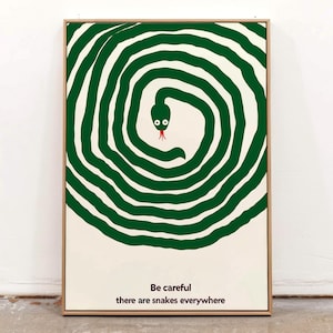 May include: A framed art print with a green snake in a spiral design on an off-white backdrop. The snake has a red tongue, and the text reads "Be careful there are snakes everywhere."