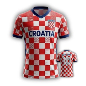 May include: Red and white checkered Croatia soccer jersey with blue accents. The word "CROATIA" is across the chest. A smaller jersey with "YOUR NAME" and the number "10" is also visible.