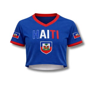 May include: A blue crop top with red trim and the word "HAITI" in white and red. The shirt features the Haitian flag on the sleeves and a crest on the front. The top has a V-neck design.