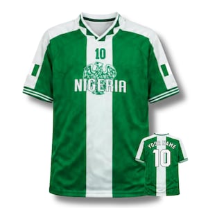Puede incluir: Camiseta de fútbol verde y blanca de Nigeria con el número 10 en la parte delantera y trasera. La parte delantera presenta la palabra "NIGERIA" y un emblema de águila. La camiseta tiene una franja blanca en el centro y detalles blancos en las mangas.