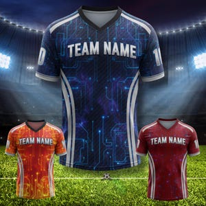 May include: Three soccer jerseys with a digital circuit design. The jerseys are in blue, orange, and red, each with the text "TEAM NAME" across the chest. White accents and numbers are visible on the sleeves.