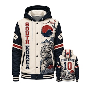 May include: A cream and navy blue varsity-style hoodie featuring a tiger illustration, South Korea text, and the South Korean flag. The front has a button-up placket, while the back displays the text Your Name and the number 10 with a tiger graphic.