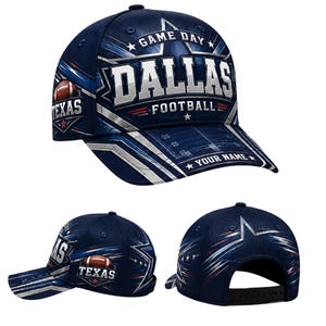 Puede incluir: Una gorra de béisbol azul marino con una gran estrella plateada, el texto GAME DAY DALLAS FOOTBALL y un gráfico de balón de fútbol con la palabra TEXAS. La visera muestra un campo de fútbol y el texto YOUR NAME, con una correa negra ajustable.