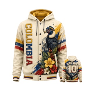 May include: A cream-colored button-up hoodie featuring the word COLOMBIA in yellow, blue, and red letters. The front displays an Andean condor, flowers, and mountain scenery. The back shows the text YOUR NAME above the number 10 and a condor graphic.