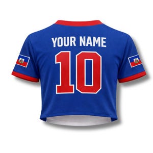 May include: Blue crop top jersey with red trim and the number 10 in red with a white outline. The text "YOUR NAME" is above the number. The Haitian flag is on each sleeve.