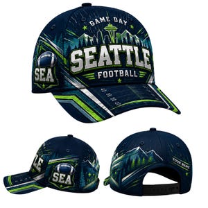 Pode incluir: Um boné de beisebol azul-marinho com uma estampa gráfica do horizonte de Seattle, da Space Needle e montanhas. O texto diz "GAME DAY", "SEATTLE FOOTBALL" e "SEA". O design inclui um ícone de bola de futebol americano e linhas de campo.