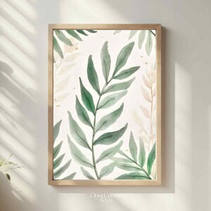 May include: A framed watercolour print featuring green leaves on a white backdrop. The leaves are in shades of green, with gold flecks. The artwork is set in a light wood frame and has a botanical theme, suitable for home decor.
