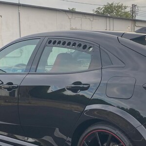 May include: Black Honda Civic Type R with red accents on the wheels and brake calipers. The car has a large rear spoiler and side skirts. The car is parked on an asphalt surface.