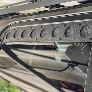 May include: Black metal vent covers with a mesh screen and multiple round holes. The vent covers are installed on a black vehicle.