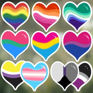 Op de afbeelding: Een verzameling van elf hartvormige stickers met diverse kleurenpatronen van pride-vlaggen. De ontwerpen bevatten golvende regenbogen, oranje en roze, groenblauw en blauw, roze en blauw, geel en blauw, en andere gestreepte kleurcombinaties.
