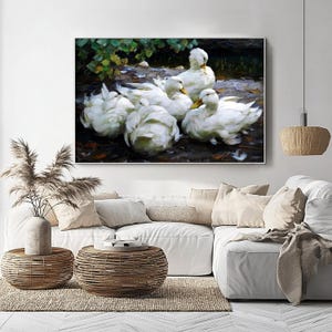 May include: An artwork shows a group of white ducks with yellow beaks near water and foliage. The painting has a soft, impressionistic style, with visible brushstrokes and a muted colour palette. The artwork is displayed above a white sectional sofa.