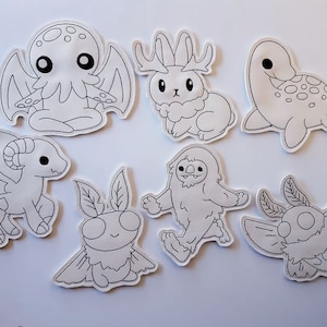 May include: Set of eight black and white iron-on patches featuring various cute cartoon creatures, including a dragon, a moth, a sloth, a bunny, a turtle, and a Cthulhu-like creature.