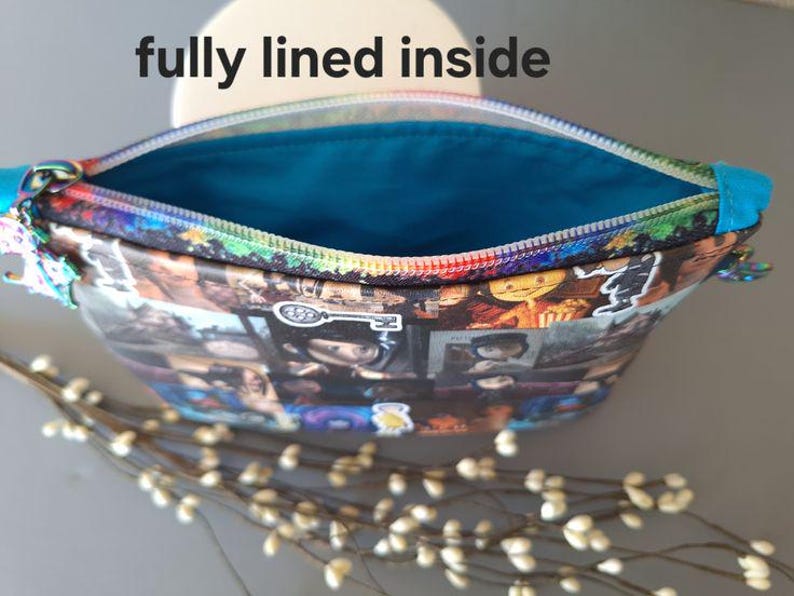May include: A colorful zippered pouch with a blue lining. The pouch is made of fabric and has a collage of images printed on the outside. The text "fully lined inside" is visible in the image.